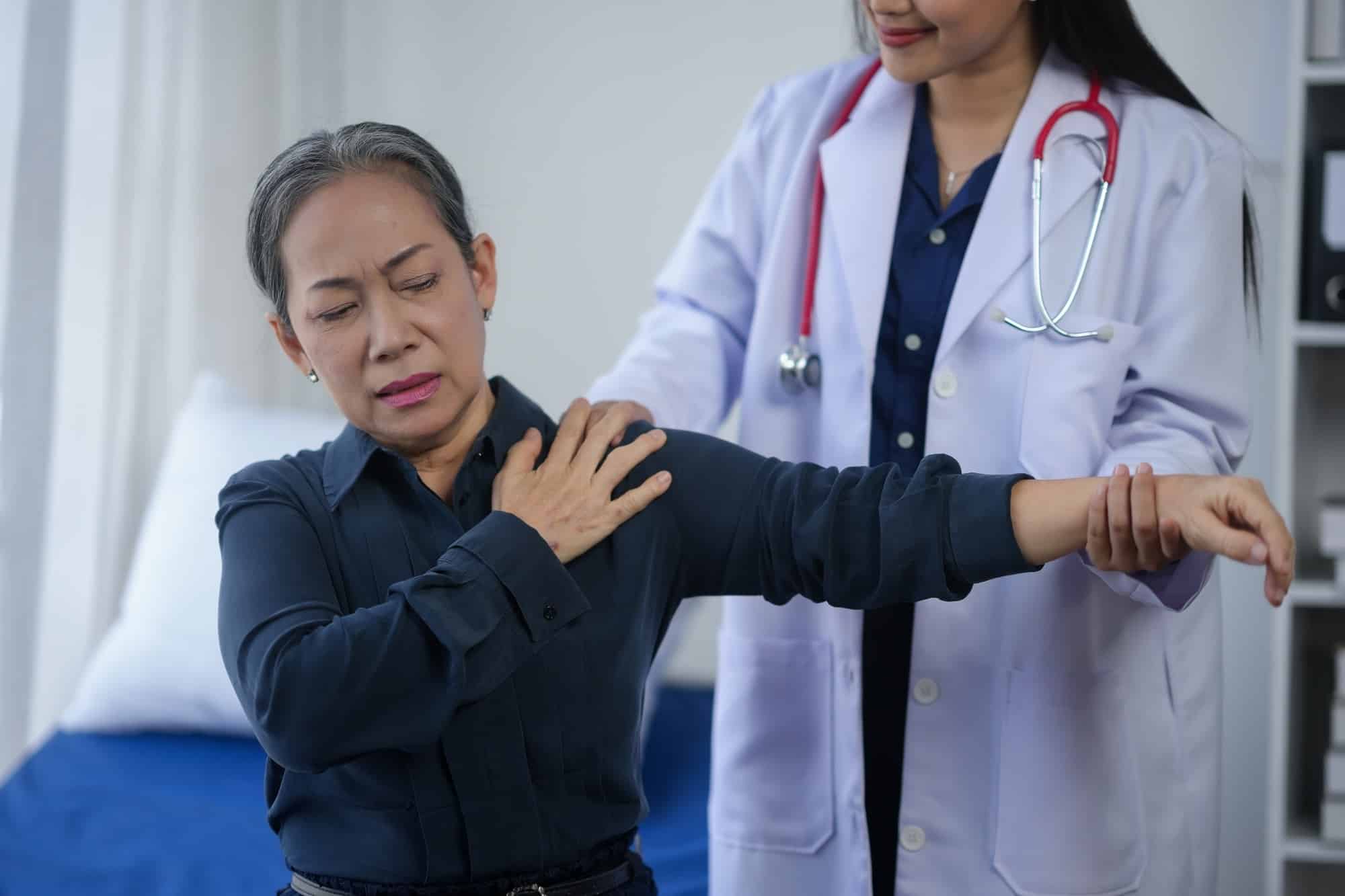 Senior woman experiencing shoulder pain during a medical examination with doctor